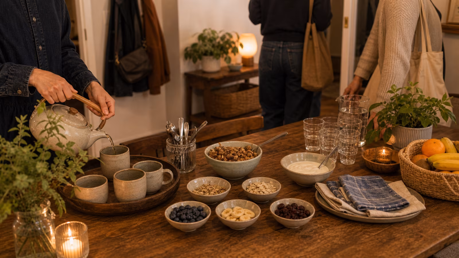 an arrival sequence at a small table with cups being filled, coats on hooks, snack toppings, and guests settling in