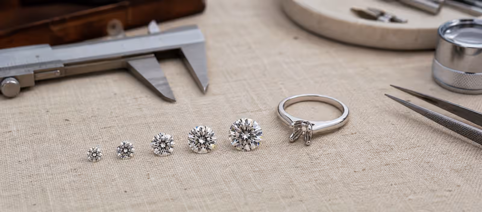 Loose diamonds of different visible sizes beside a solitaire ring setting.