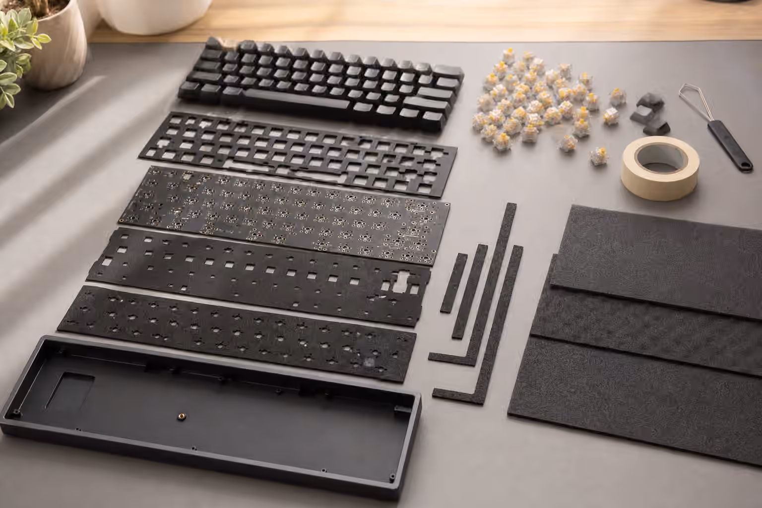 Exploded mechanical keyboard with foam sheets, tape, gasket strips, switches, and case layers.