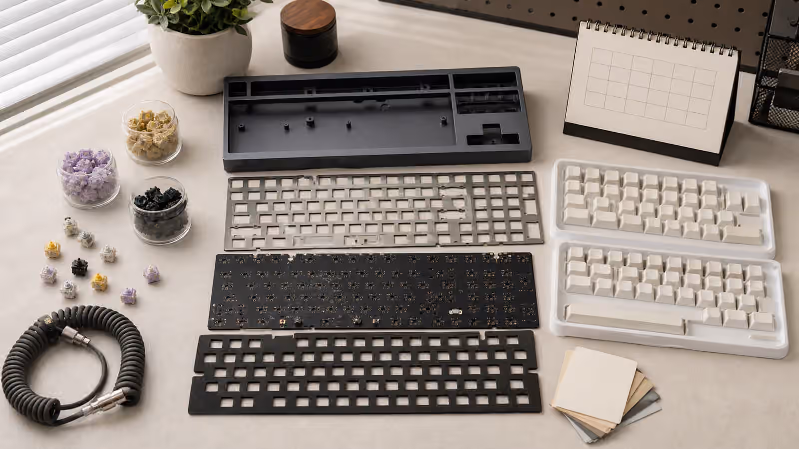 Unassembled mechanical keyboard kit with blank keycaps, switches, case parts, cable, and a blank planning card.