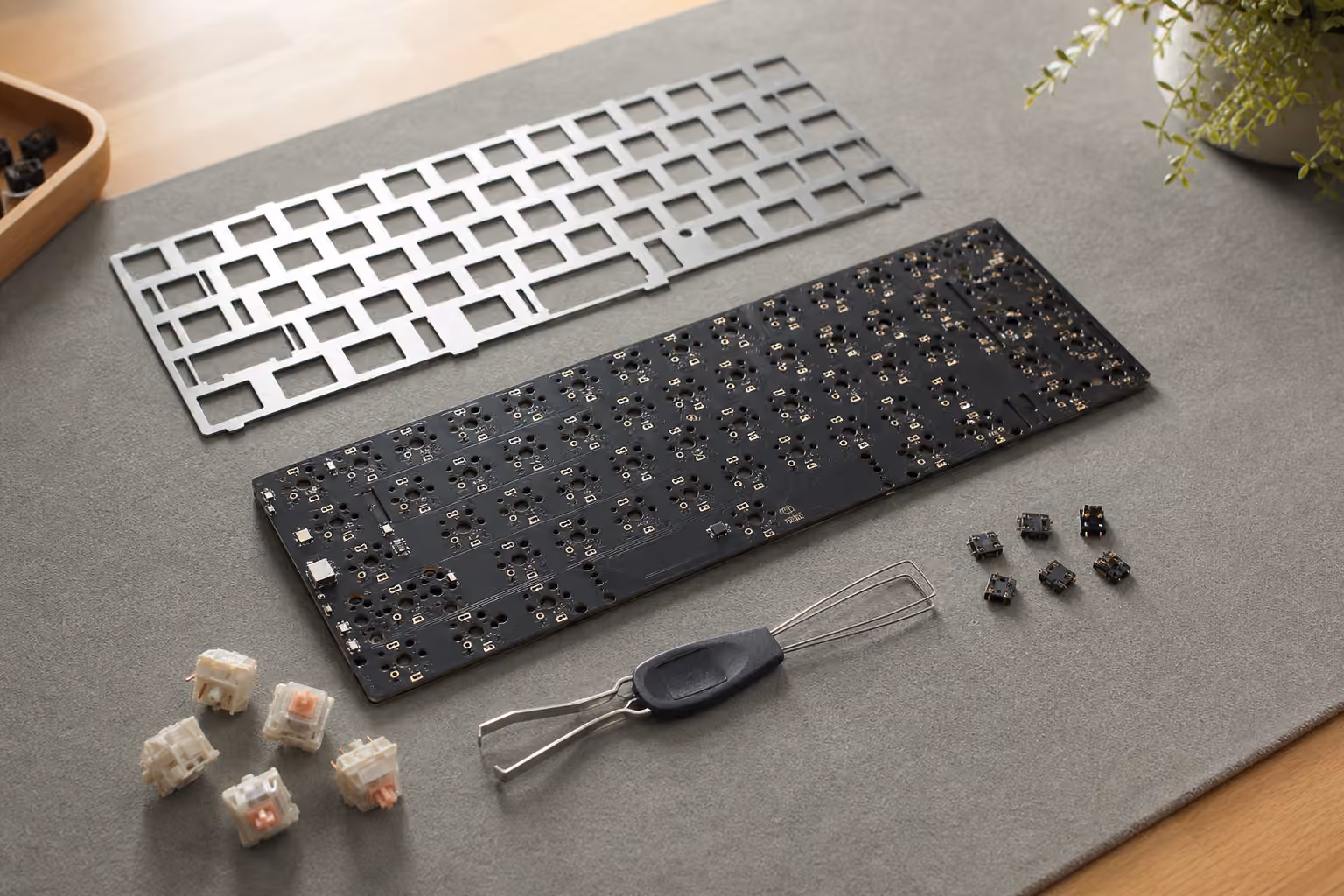 Mechanical keyboard PCB with plate, loose switches, hot-swap sockets, and a switch puller.