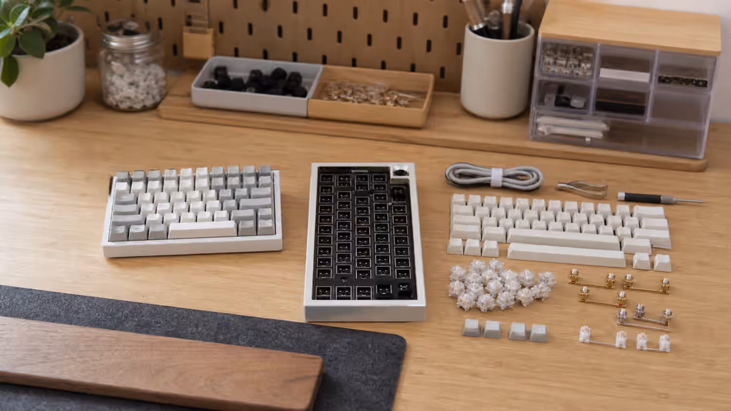 Finished keyboard, barebones case, and keyboard kit parts arranged on a desk.