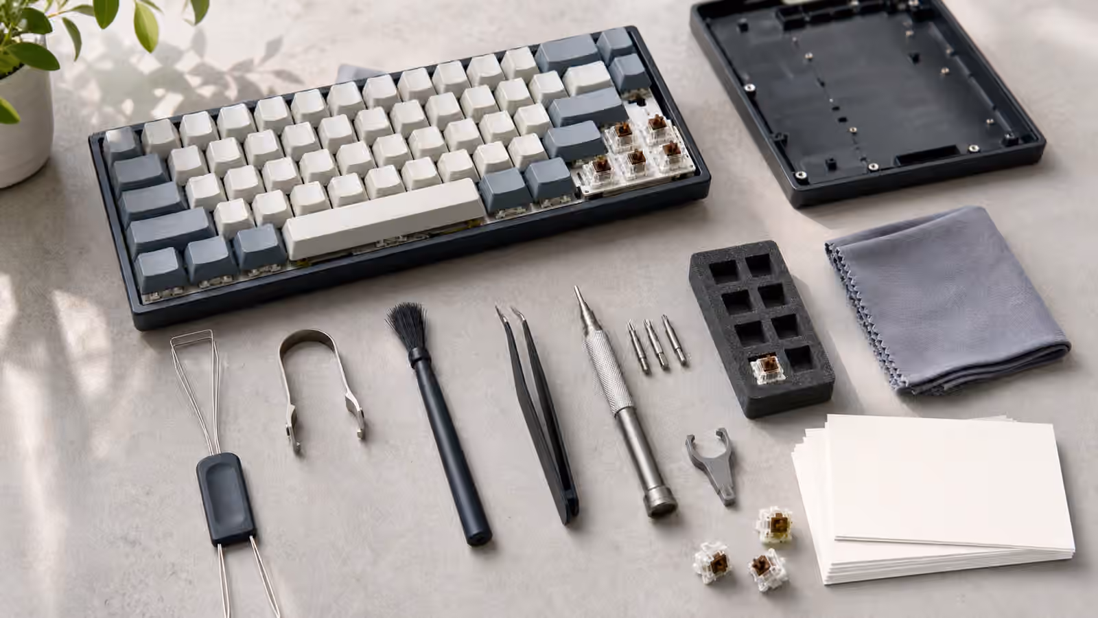Mechanical keyboard tool kit arranged beside a partly opened compact keyboard.