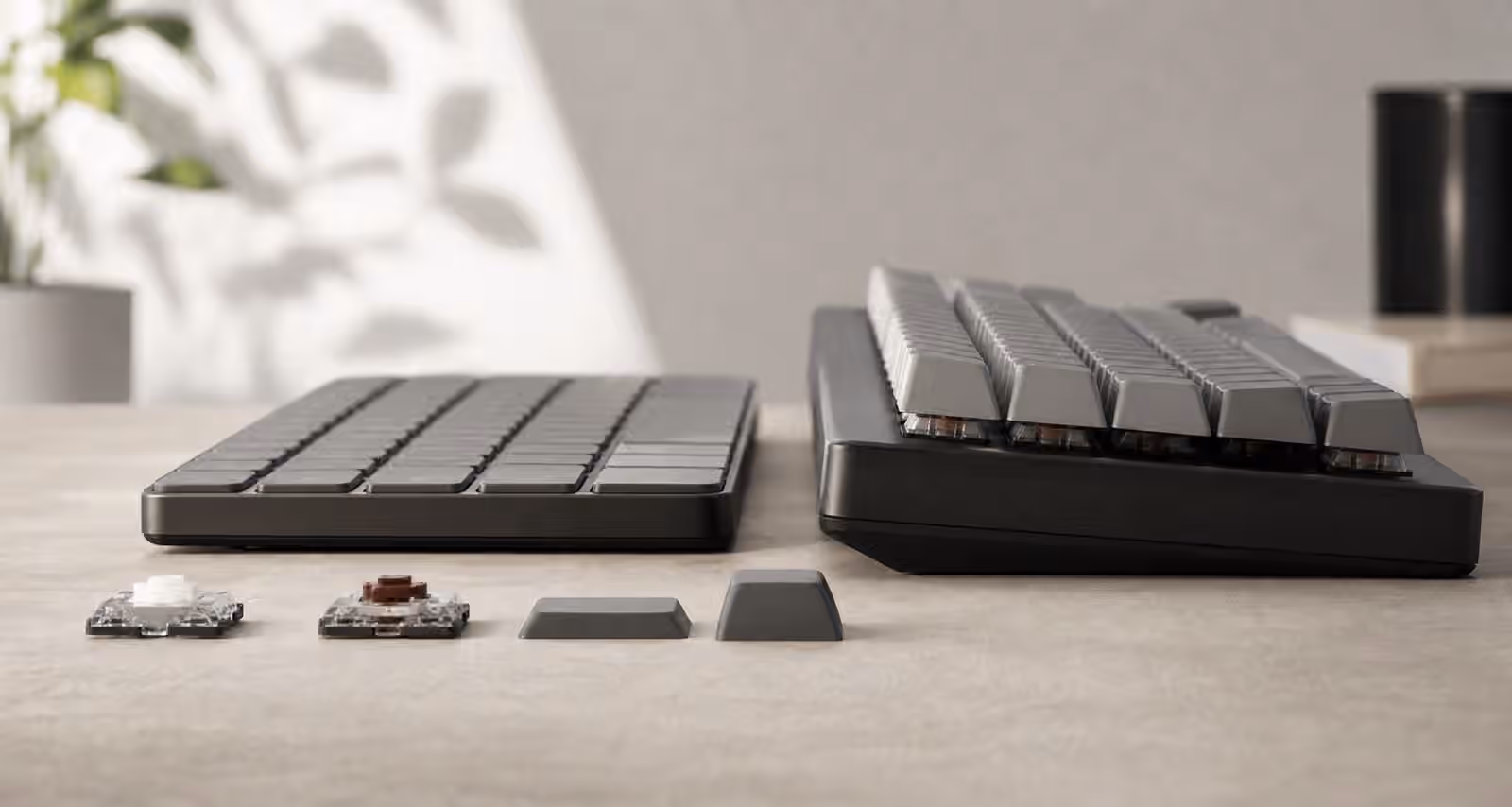 Low-profile mechanical keyboard beside a taller mechanical keyboard with loose switches and keycaps.