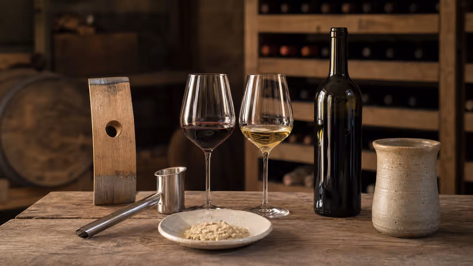 Wine glasses and cellar tools on a wooden tasting table.